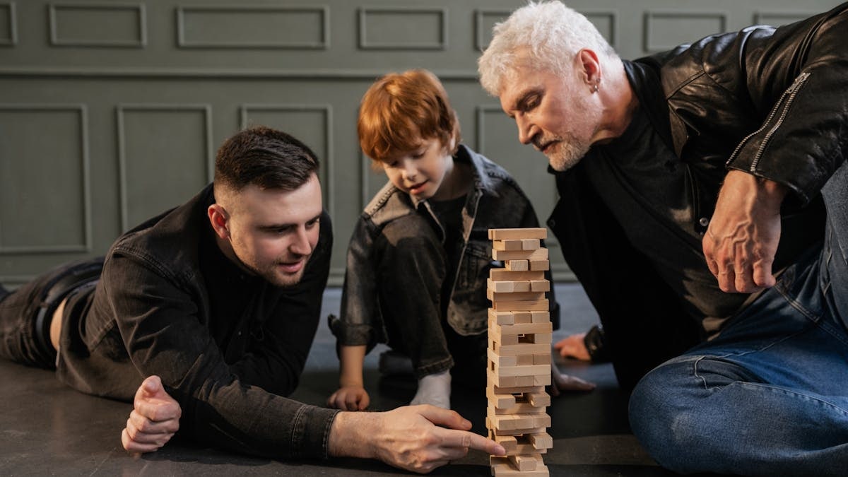 A joyful family scene with a grandparent, parent, and child enjoying a game of Jenga together.